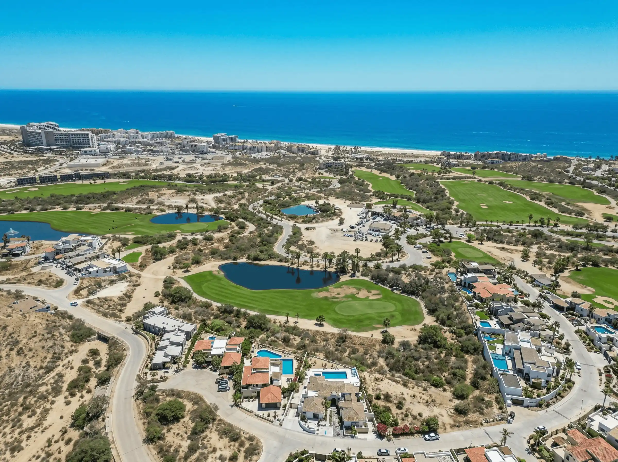 Aerial view of coastal golf course and oceanfront residential communities in Los Cabos
